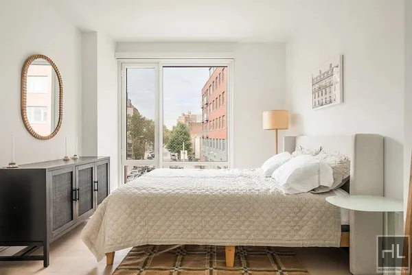a bedroom with a bed lamps and a large mirror on the dresser