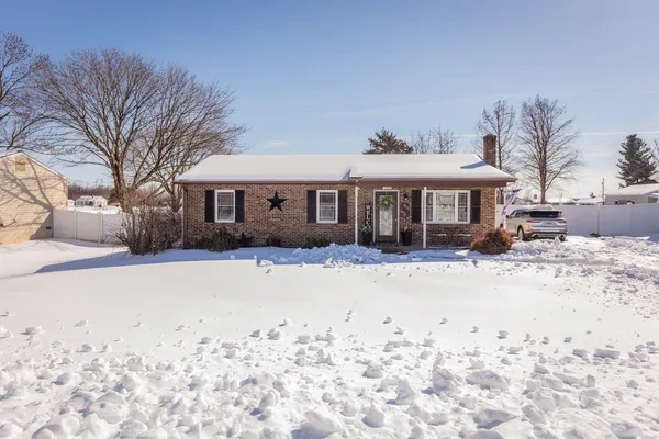 a front view of a house with a yard covered in snow