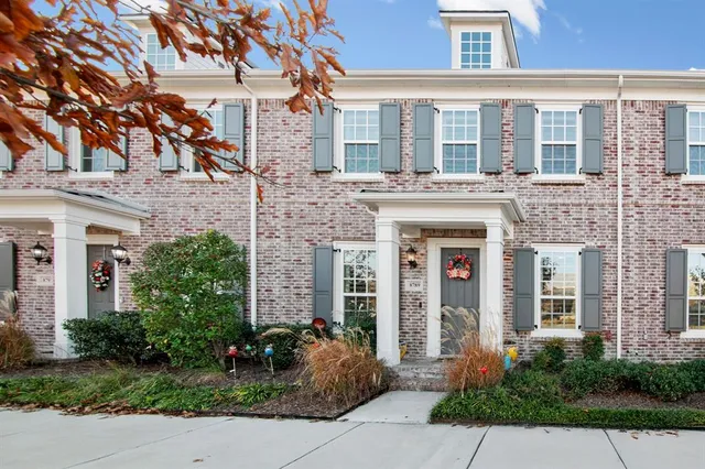 front view of a brick house with a large windows and a large tree