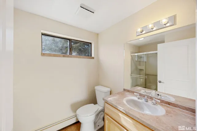 a bathroom with a granite countertop sink mirror vanity and toilet