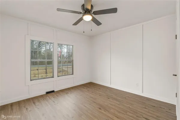 an empty room with wooden floor and windows