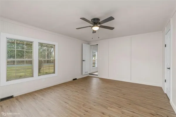 a view of an empty room with a window and wooden floor