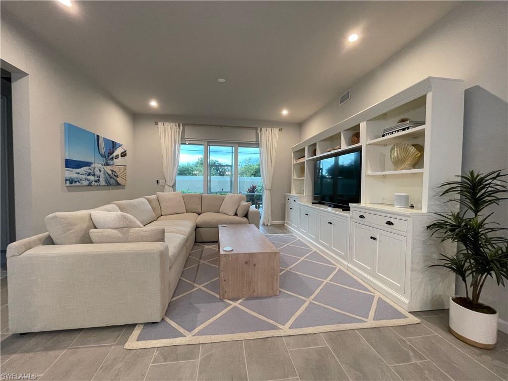 4676 Arboretum Circle, Unit 101 Naples, FL 34112 - Photo 11 of 24 a living room with furniture and a flat screen tv