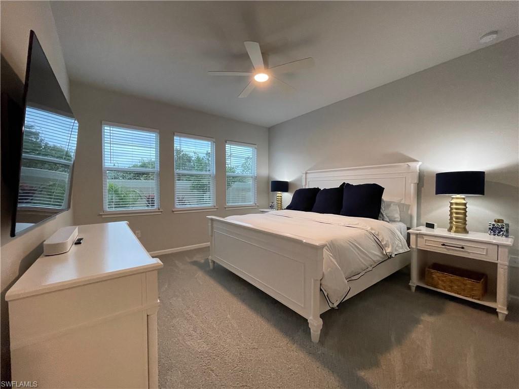 4676 Arboretum Circle, Unit 101 Naples, FL 34112 - Photo 13 of 24 a bedroom with a large bed and a flat tv screen on dresser