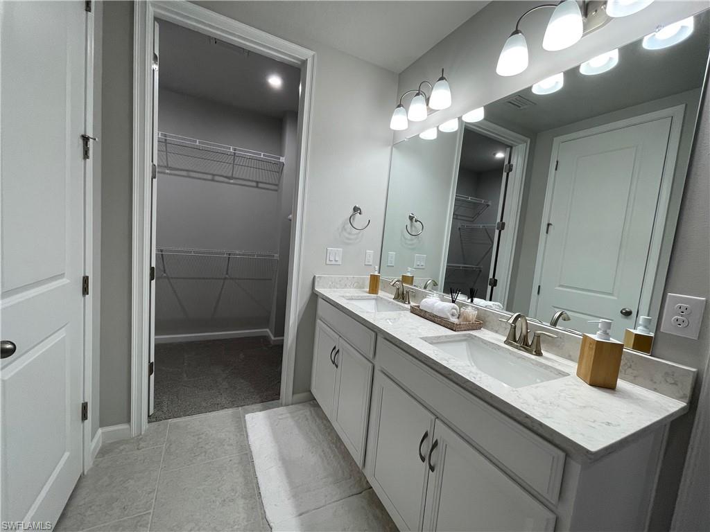 4676 Arboretum Circle, Unit 101 Naples, FL 34112 - Photo 14 of 24 a bathroom with a sink a light fixture and a mirror