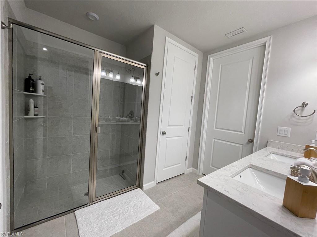 4676 Arboretum Circle, Unit 101 Naples, FL 34112 - Photo 15 of 24 a bathroom with a granite countertop sink mirror and shower