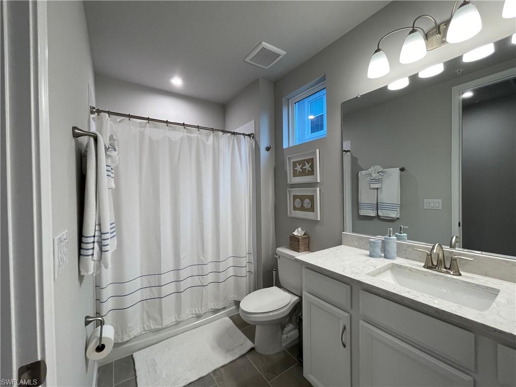 4676 Arboretum Circle, Unit 101 Naples, FL 34112 - Photo 19 of 24 a bathroom with a toilet sink and a mirror
