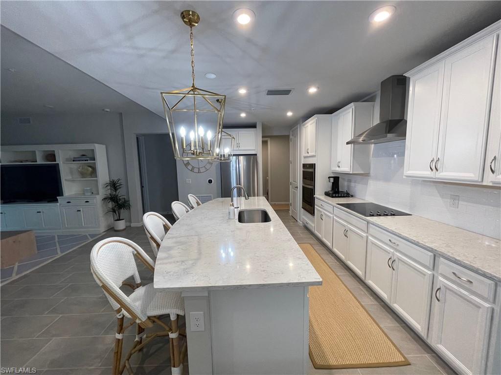 4676 Arboretum Circle, Unit 101 Naples, FL 34112 - Photo 4 of 24 a large kitchen with stainless steel appliances kitchen island granite countertop a sink a stove a dining table and chairs