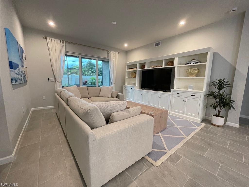 4676 Arboretum Circle, Unit 101 Naples, FL 34112 - Photo 9 of 24 a living room with furniture a large window and a flat screen tv