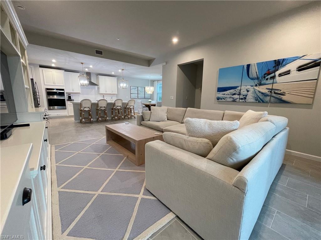 4676 Arboretum Circle, Unit 101 Naples, FL 34112 - Photo 10 of 24 a living room with patio furniture and a view of kitchen