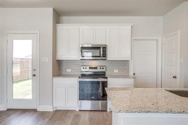a kitchen with white cabinets and appliances