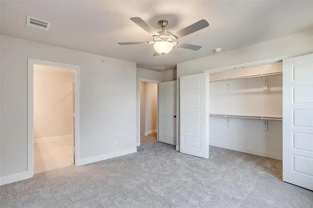 an empty room with chandelier fan and windows