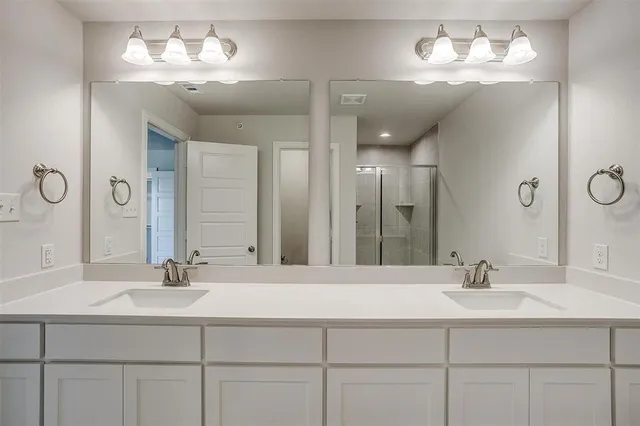 a bathroom with double vanity sinks a vanity a lamp and a mirror