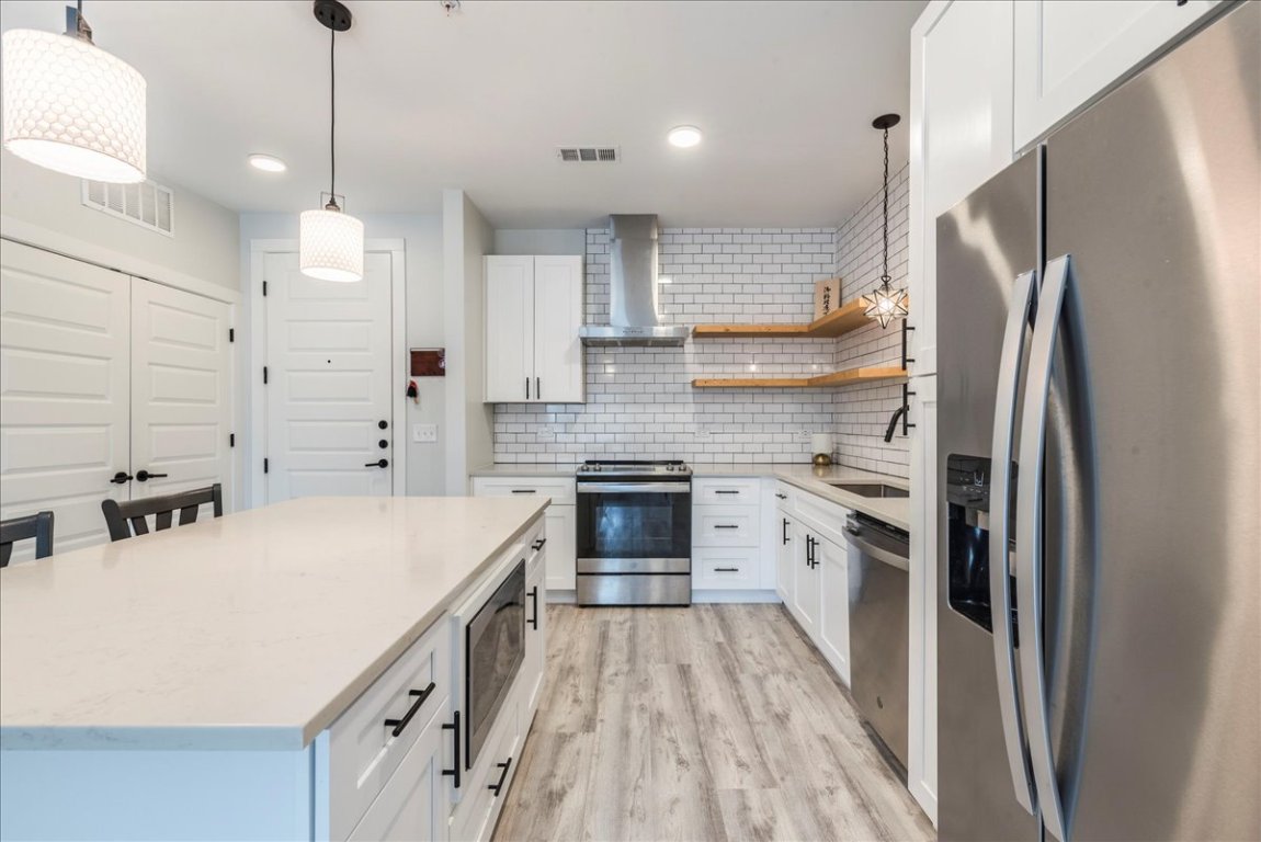 3101 Govalle Avenue, Unit 220 Austin, TX 78702 - Photo 3 of 26 a kitchen with a refrigerator a sink and dishwasher a oven with wooden floor