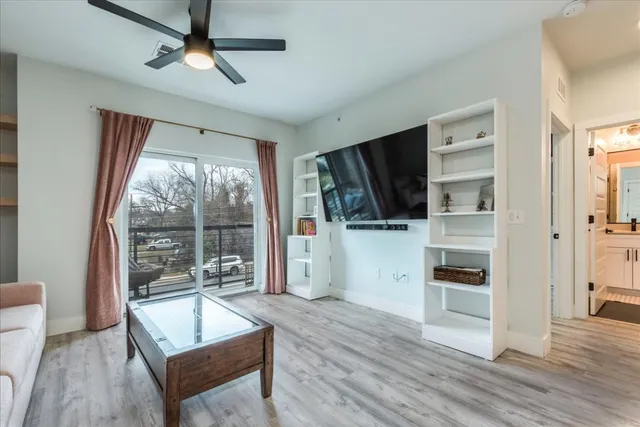 a living room with furniture a flat screen tv and a floor to ceiling window