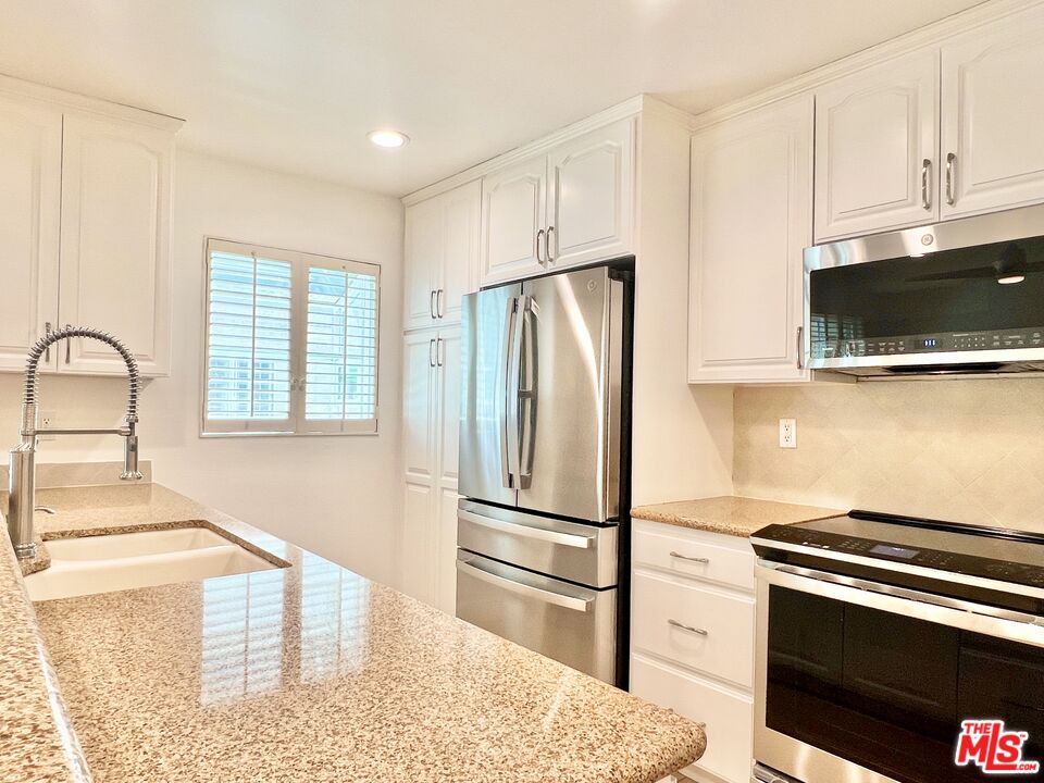 13218 Fiji Way, Unit B Marina del Rey, CA 90292 - Photo 21 of 63 a kitchen with granite countertop a refrigerator stove and microwave