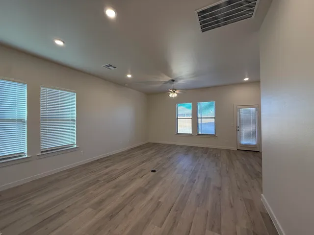 an empty room with wooden floor and windows