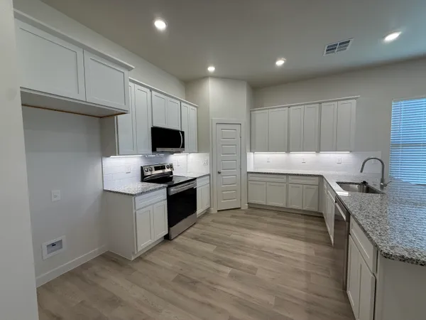 a kitchen with granite countertop a sink and a stove top oven with wooden floor