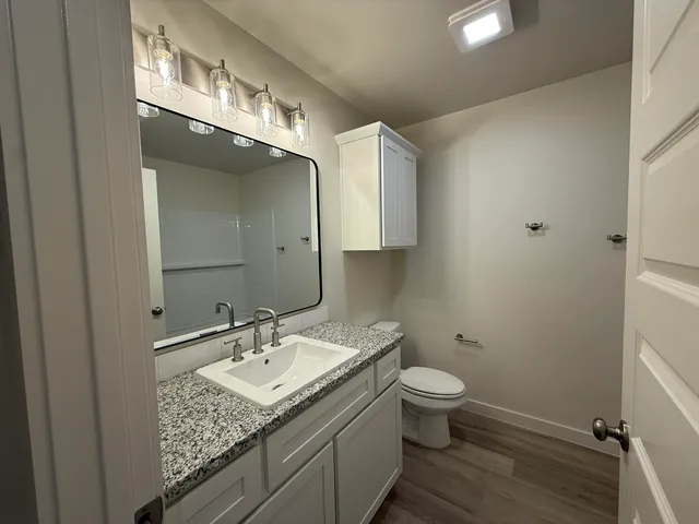a bathroom with a granite countertop sink a toilet and a mirror