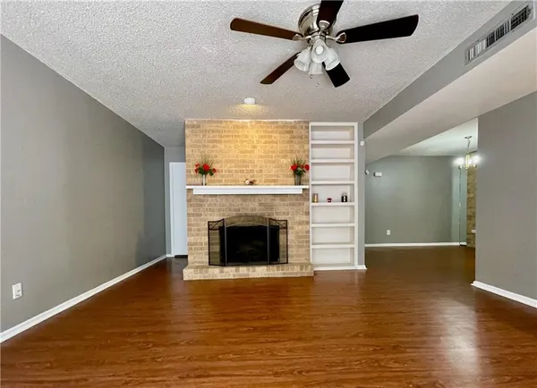 a view of an empty room with wooden floor fireplace and a window