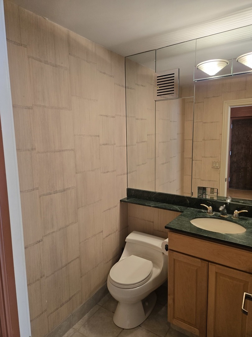 40 East Cedar Street, Unit 21C Chicago, IL 60611 - Photo 22 of 33 a bathroom with a granite countertop toilet sink and mirror