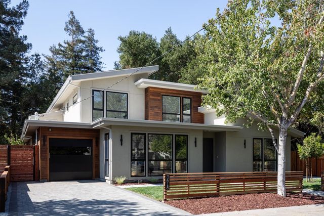 a view of a white house with large windows and a large tree