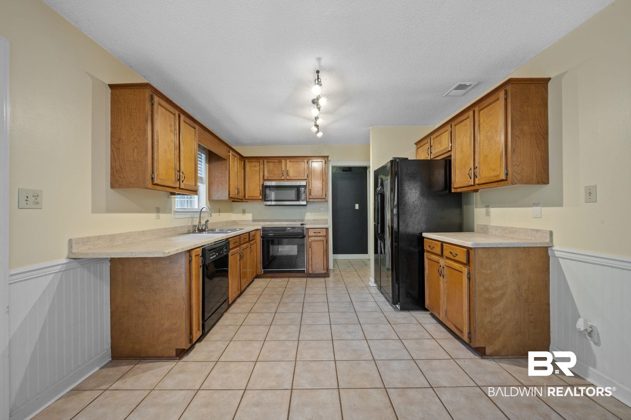 100 Montclair Loop Daphne, AL 36526 - Photo 23 of 39 Kitchen with sink, black appliances, light tile patterned flooring, rail lighting, and a textured ceiling