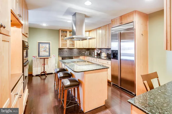 a kitchen with stainless steel appliances granite countertop a refrigerator a stove and a sink with wooden floor