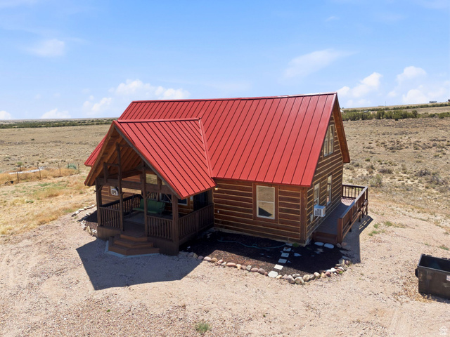 10937 South County Road, Unit 29 Duchesne, UT 84021 - Photo 34 of 41 Wood-sided cabin featuring a vibrant red metal roof, a covered front porch with wooden railings and steps, and an additional side deck with matching railings