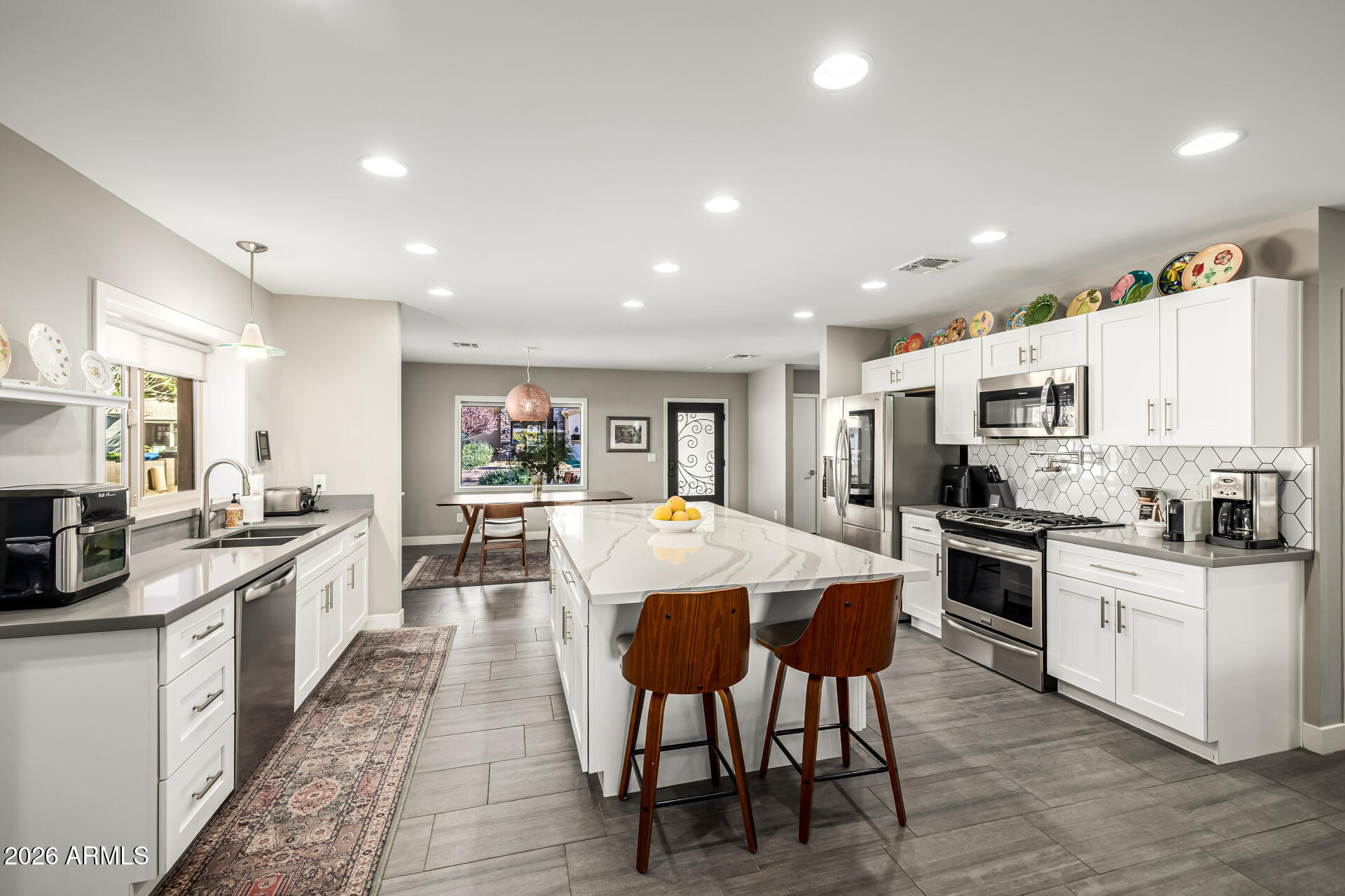 6726 North 11th Street Phoenix, AZ 85014 - Photo 15 of 49 a large kitchen with stainless steel appliances lots of white cabinets table and chairs
