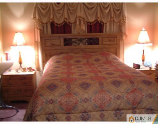 197 Evergreen Road, Unit 7B Edison, NJ 08837 - Photo 6 of 6 a spacious bedroom with a bed and a lamp