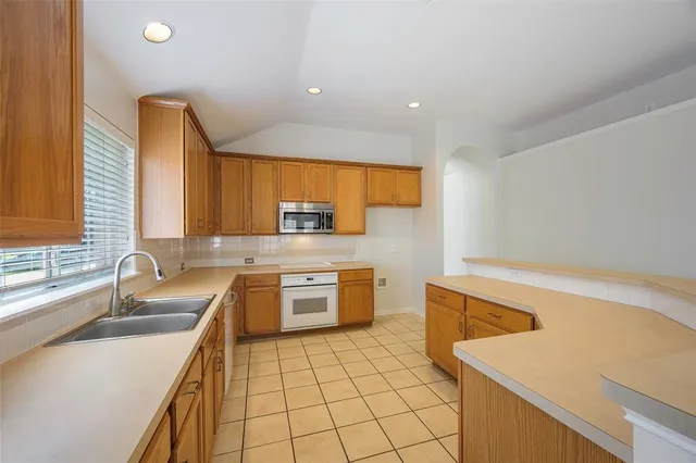 a kitchen with a sink a stove top oven a counter space and cabinets