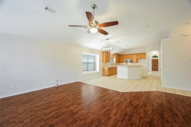 a view of empty room with wooden floor and ceiling fan