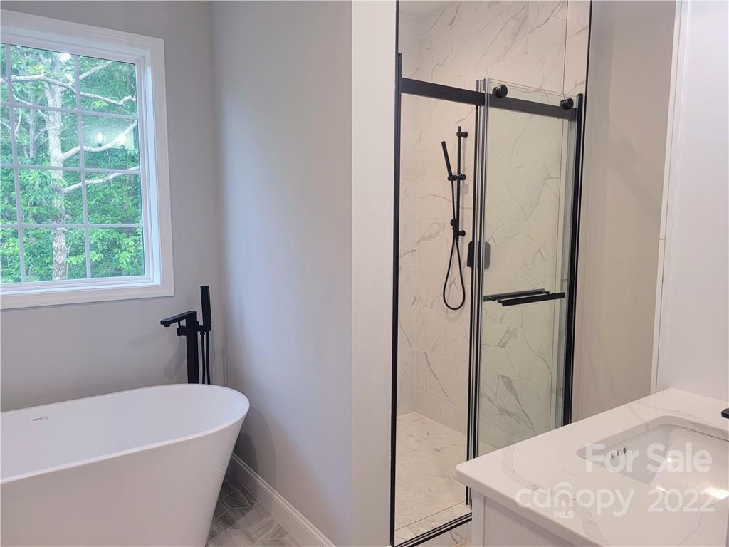 2304 Peniel Road Columbus, NC 28722 - Photo 9 of 18 a bathroom with a white bath tub a shower and a window