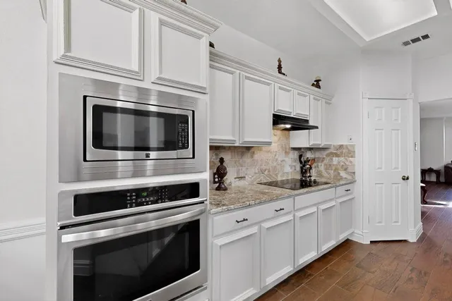 a kitchen with stainless steel appliances white cabinets a stove top oven a sink and dishwasher