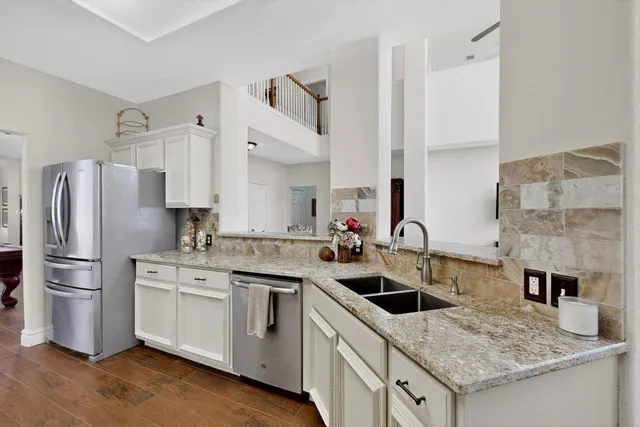a kitchen with a sink a stove a refrigerator and white cabinets