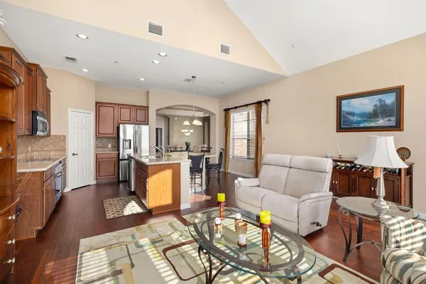 a living room with stainless steel appliances furniture a rug and a view of kitchen