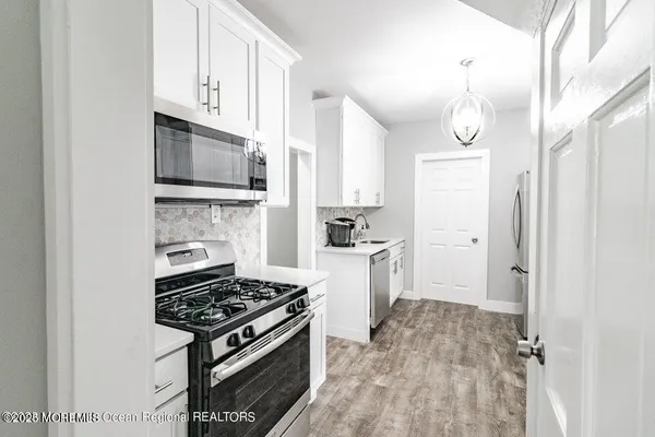 a kitchen with a refrigerator a sink cabinets and wooden floor