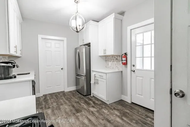 a kitchen with a refrigerator a sink cabinets and wooden floor