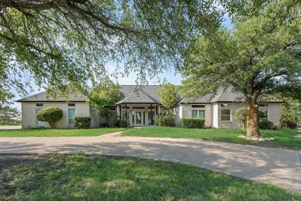a front view of a house with a yard and trees
