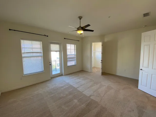 an empty room with chandelier fan and windows