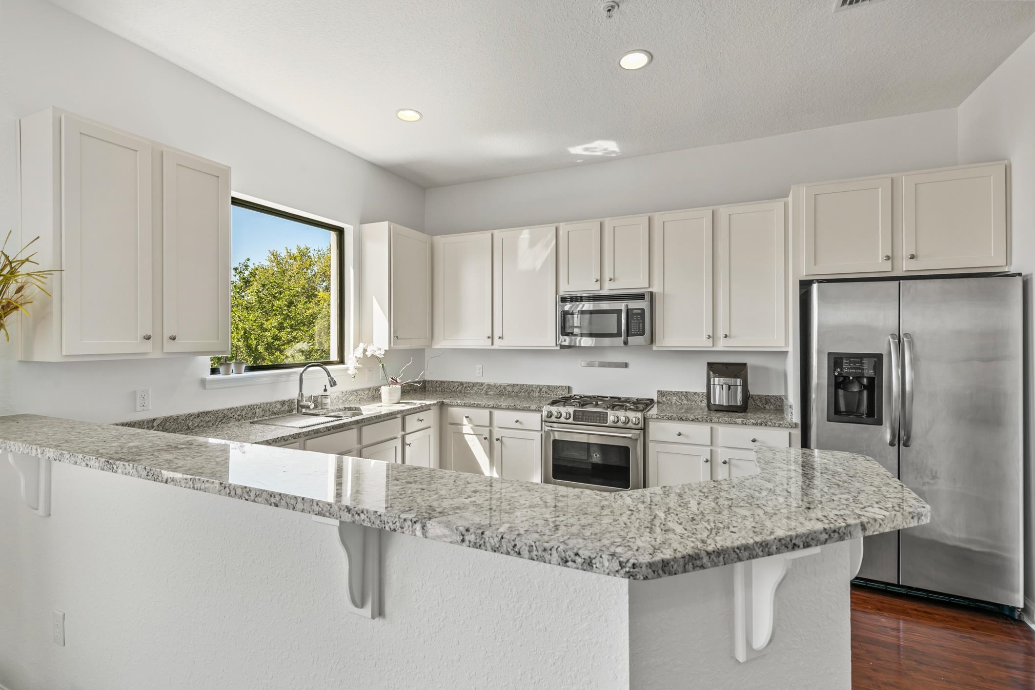 654 Market Street St. Augustine, FL 32095 - Photo 10 of 38 a kitchen with stainless steel appliances granite countertop a sink a stove a refrigerator with white cabinets and wooden floor