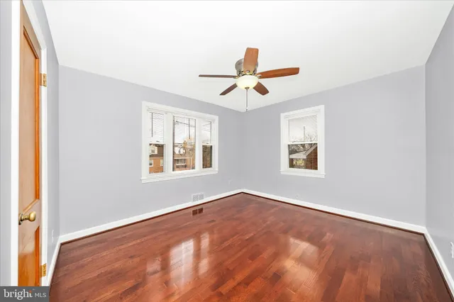 a view of an empty room with window and wooden floor