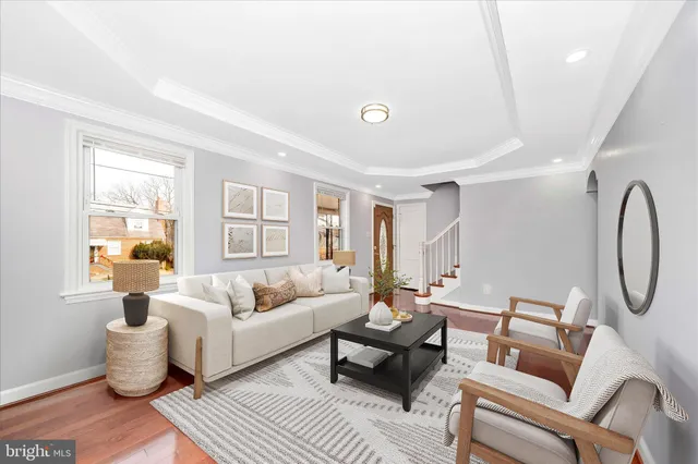 a living room with furniture a clock on wall and a window
