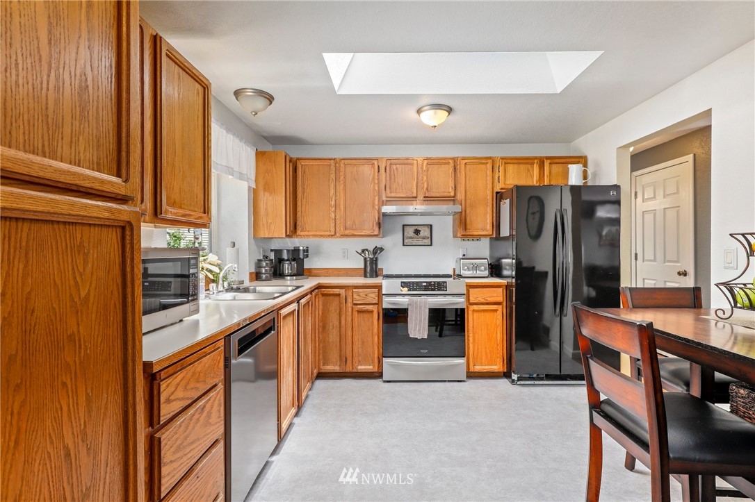 1417 234th Street Southwest Bothell, WA 98021 - Photo 7 of 40 a kitchen with stainless steel appliances granite countertop a stove top oven a refrigerator a sink and dishwasher