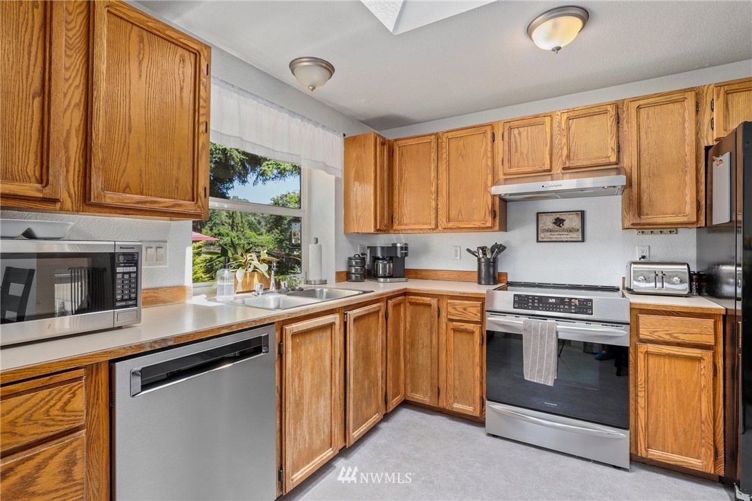 1417 234th Street Southwest Bothell, WA 98021 - Photo 8 of 40 a kitchen with stainless steel appliances granite countertop a stove a sink and a microwave