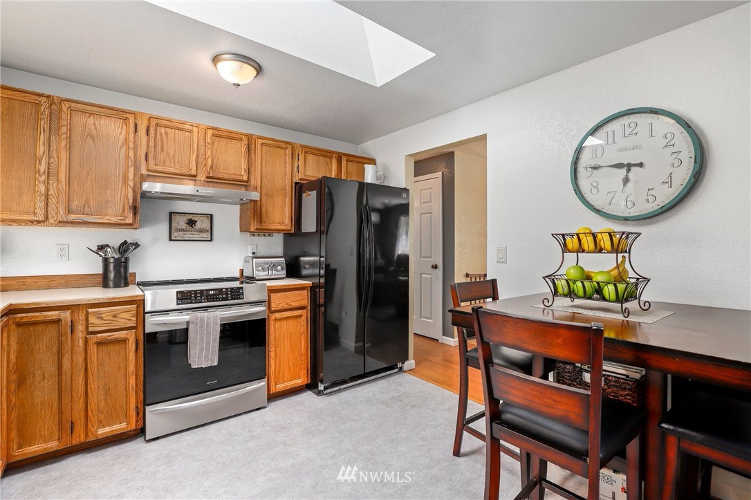 1417 234th Street Southwest Bothell, WA 98021 - Photo 9 of 40 a kitchen with stainless steel appliances granite countertop a stove a refrigerator a sink a dining table and chairs