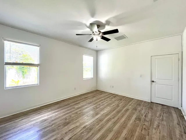 a view of empty room with wooden floor and fan