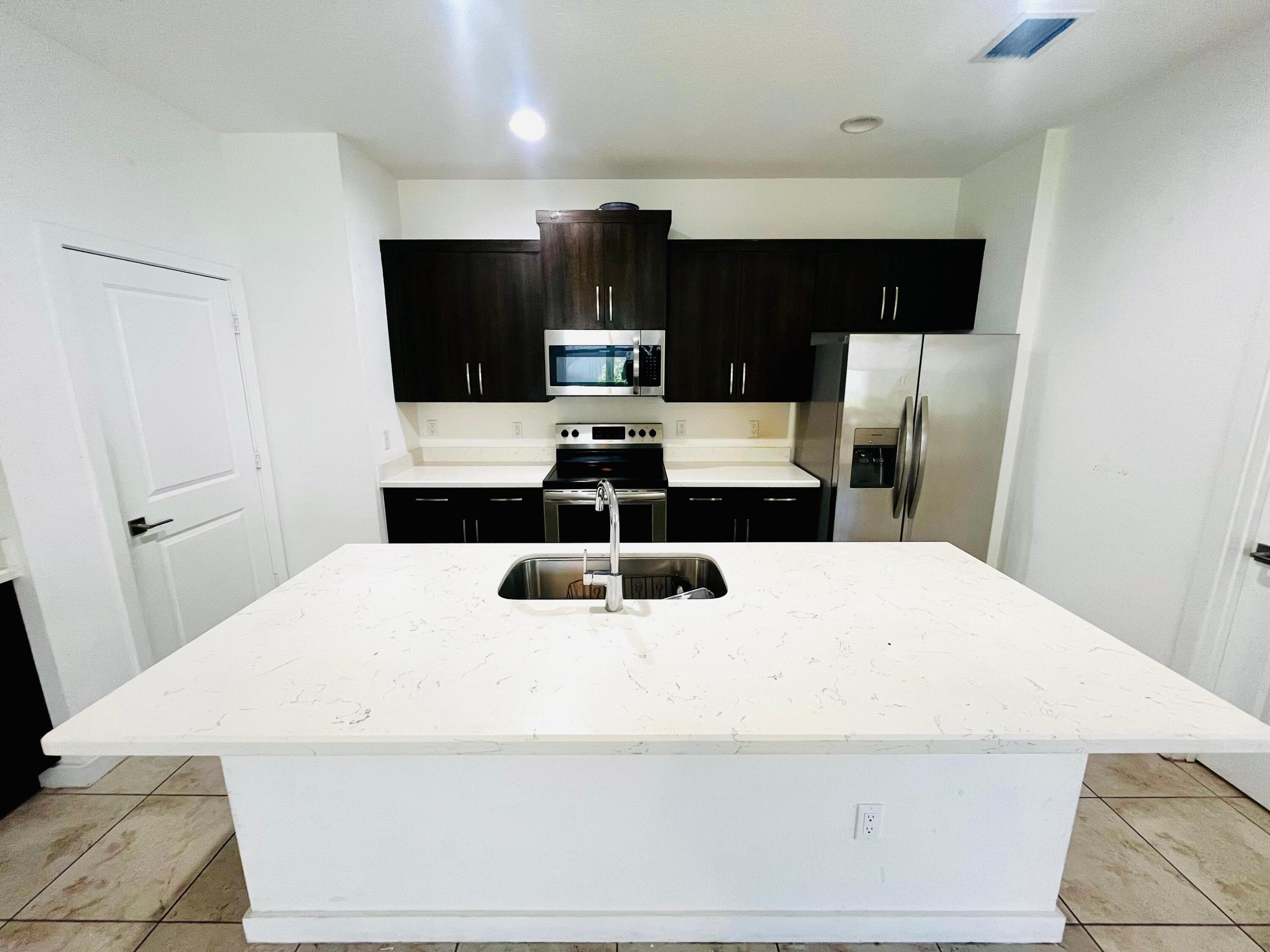 6089 Wildfire Way West Palm Beach, FL 33415 - Photo 4 of 21 a large white bed in a small kitchen