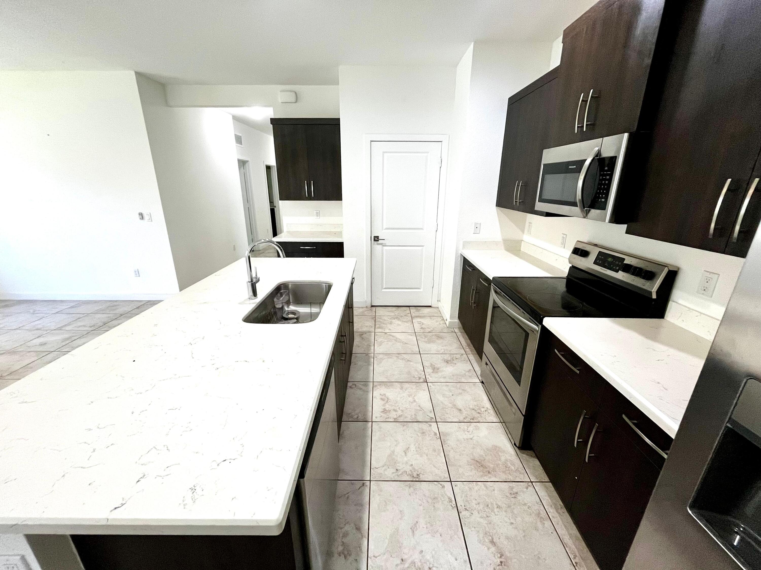 6089 Wildfire Way West Palm Beach, FL 33415 - Photo 7 of 21 a kitchen with stainless steel appliances a stove microwave and sink